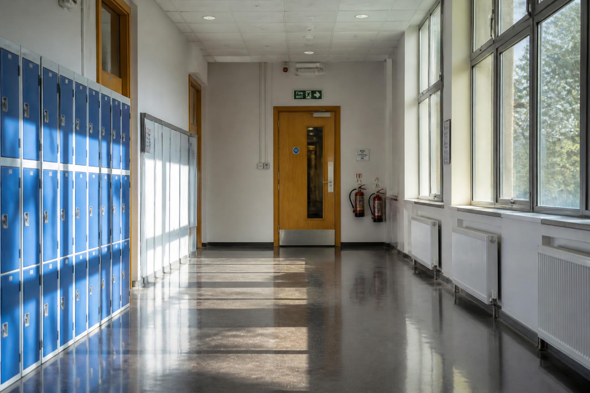 A school corridor with fire doors, extinguishers and signage in morning daylight